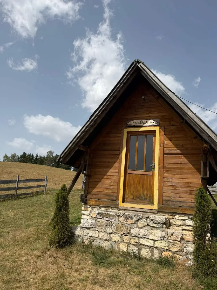 Mala drvena vikendica sa natpisom Višnja na livadi