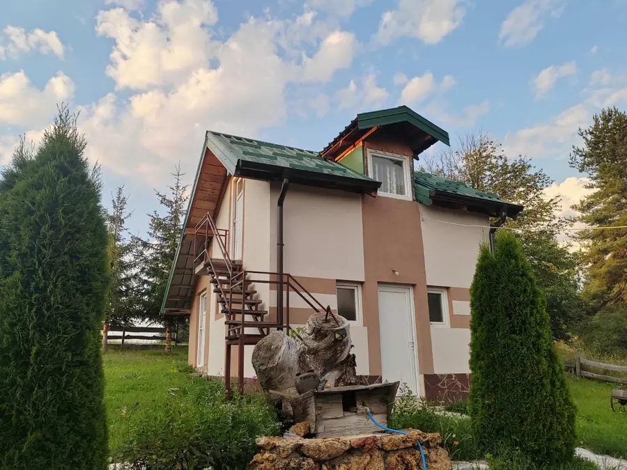 Zidana vikendica sa zelenim krovom i uređenim dvorištem